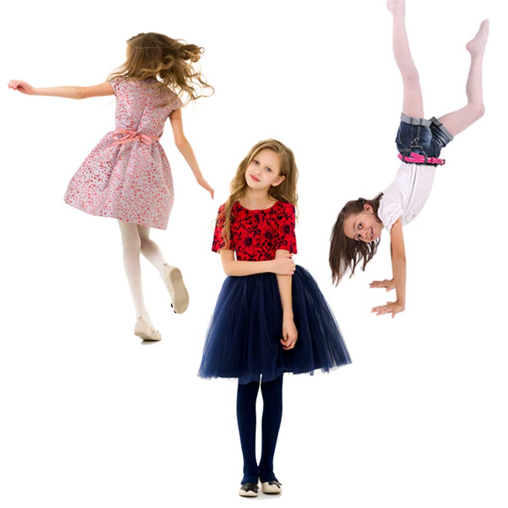 Three young girls in various poses: one dancing joyfully in pink party dress, one standing thoughtfully in red top and navy tulle skirt, one doing handstand in white top and jean shorts.