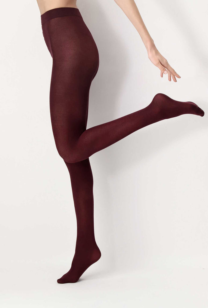 Side view of lady's leg kicking back, wearing dark red tights.