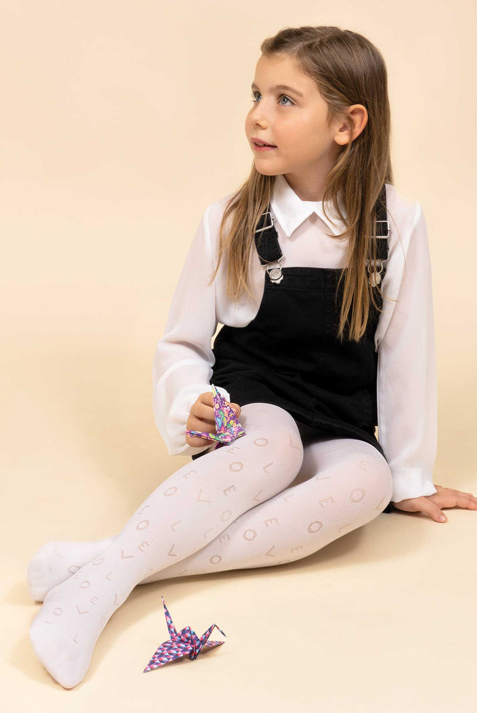 Young girls sitting on the floor wearing white tights, patterned with the words love, black pinafore and white shirt.