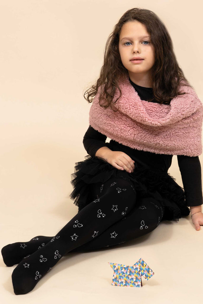 Young girl, sitting on the floor with legs outstretched in black tights, with sliver sequin motifs, black dress and pink shawl.