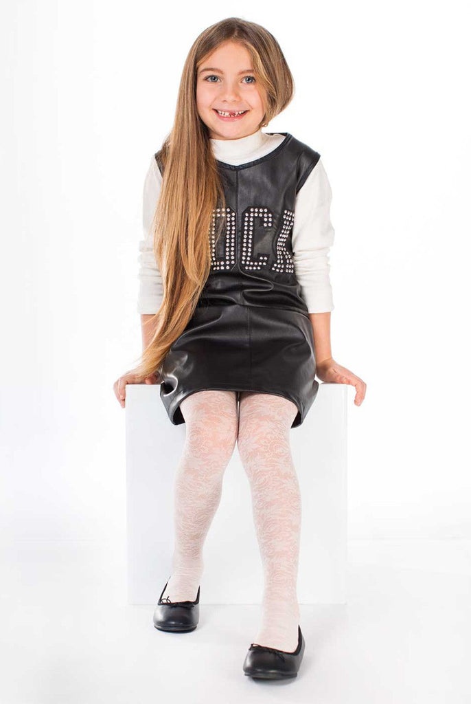 Smiling girl sitting down wearing a black dress and white floral tights.