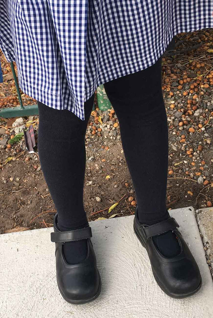 Girls' lower legs in navy tights and school uniform.