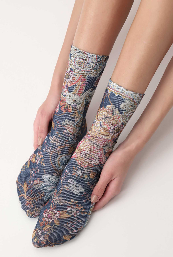 Lady's feet cradled by her hands in oriental floral print socks.