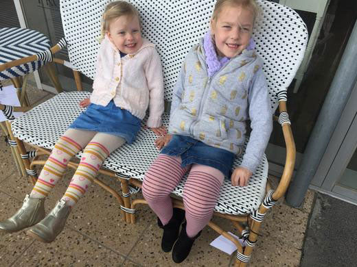 Two younger girls sitting happily wearing bright coloured tights.