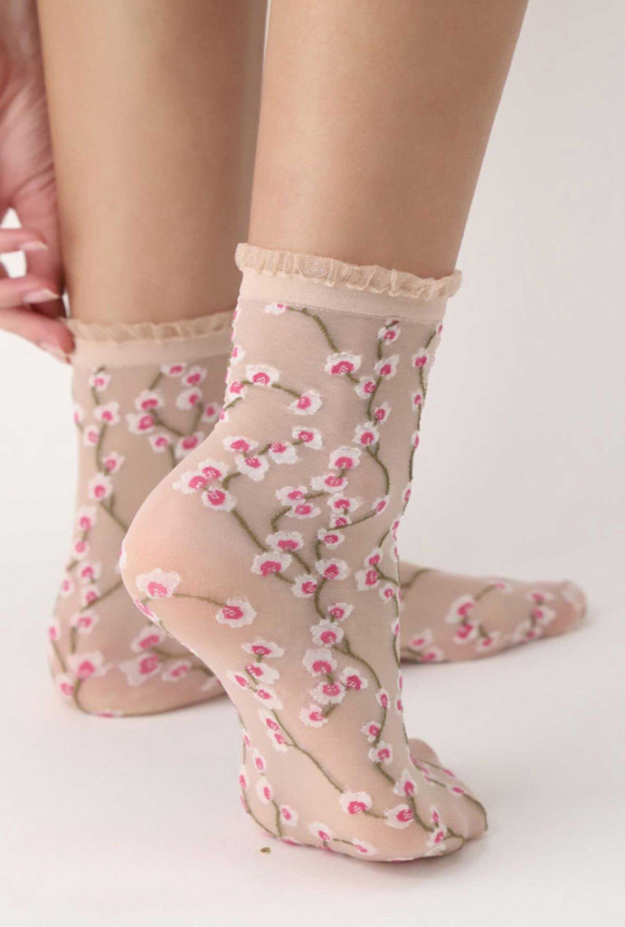 Back of woman's feet wearing sheer floral print socks.