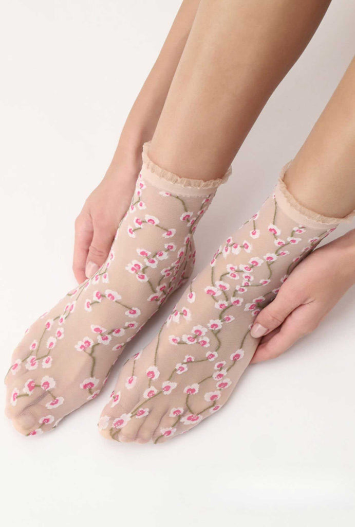 Side view of lady's feet, wearing sheer flower print socks.