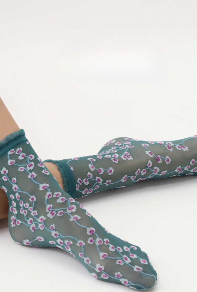 Lady's feet, outstretched and wearing sheer, flower pattern socks.