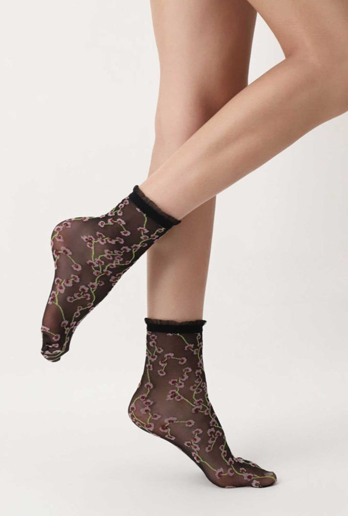 Side view of lady's legs, wearing black, sheer ,floral ,socks.