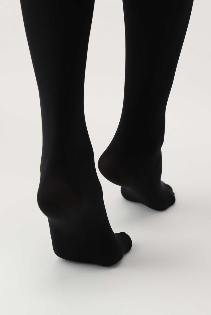 Back view of ladys feet, walking and wearing black tights.