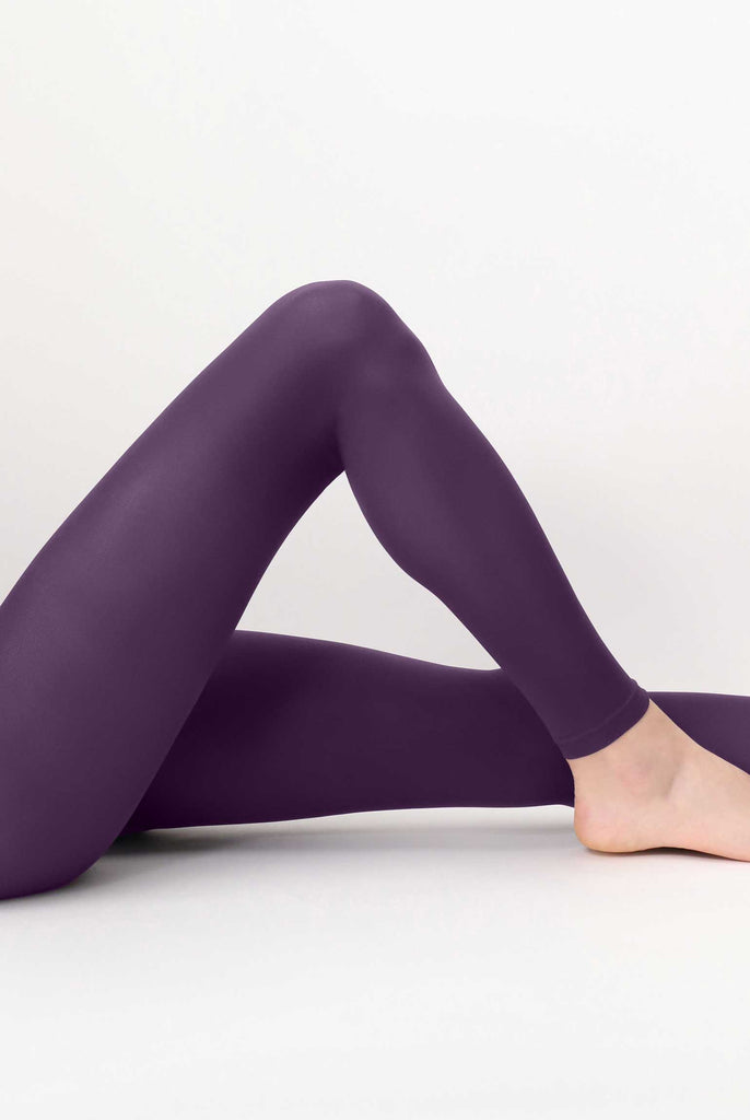 Side view of lady's outstretched legs, raised at one knee, wearing purple leggings.