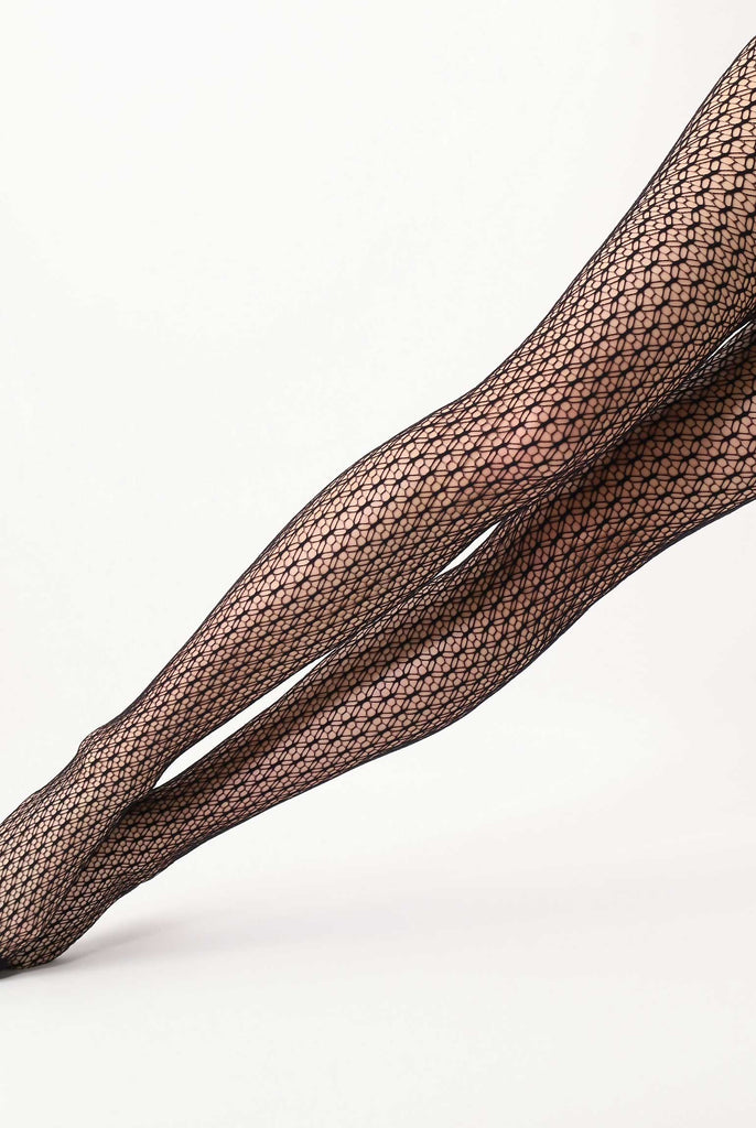 Lady's legs outstretched on an angle in black pattern mesh tights.