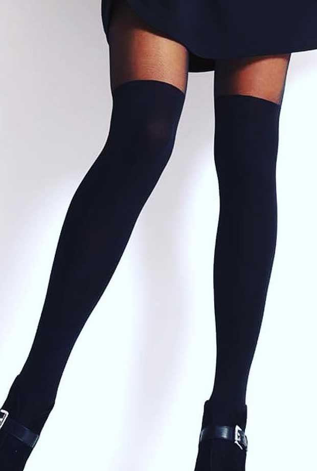 Close up of lady's legs, slightly part wearing lack long , over knee socks and black buckled shoes.