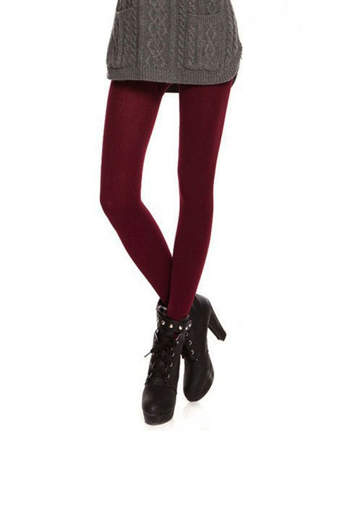 Front view of ladies legs crossed at the ankles wearing dark red tights, black boots and a grey jumper.