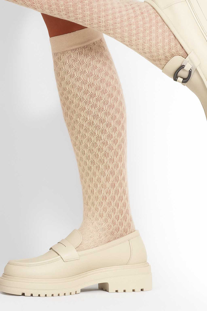 Lady's lower legs wearing cream patterned knee high socks.