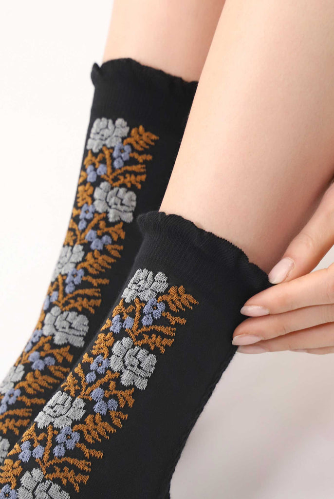 Close up of lady's lower calves displaying black and floral patterned socks.