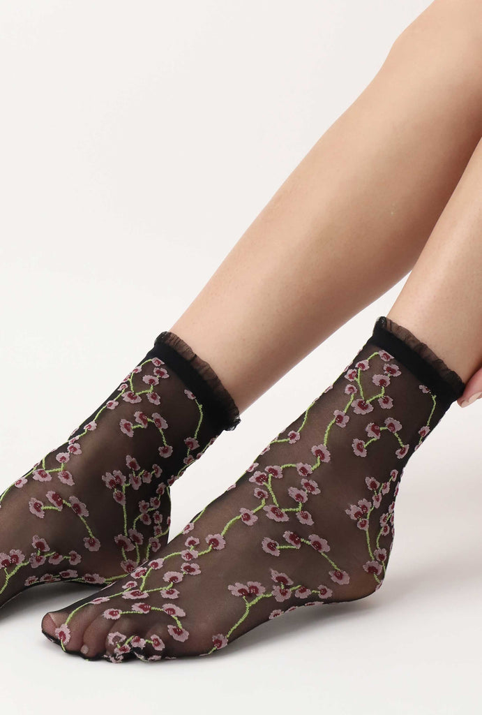 Close up of lady's feet wearing black flower print sheer socks.