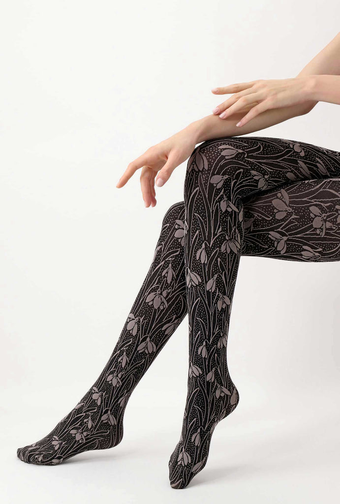 Close up of lady's lower legs, crossed and wearing grey and black flower tights.