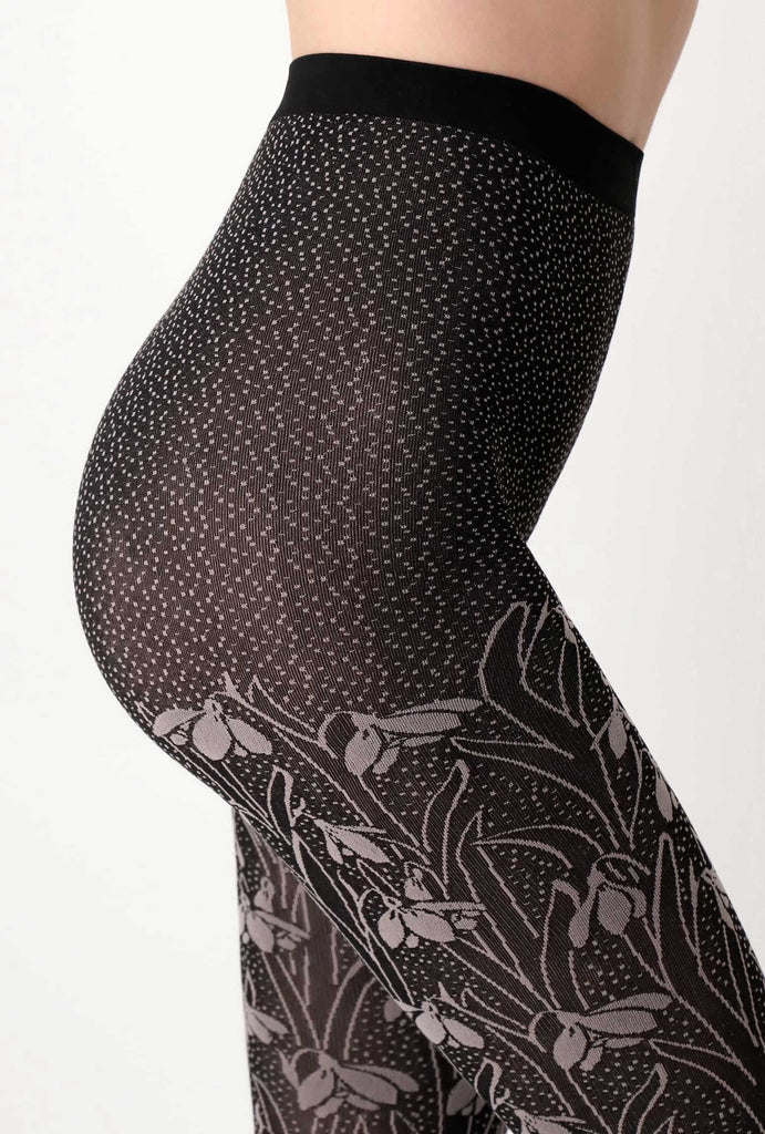 Close up of lady's side abdomen, wearing black and grey flower patterned tights.
