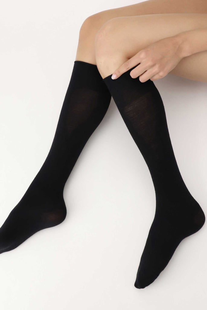 Side view of lady's lower legs in V formation, wearing black knee high socks.