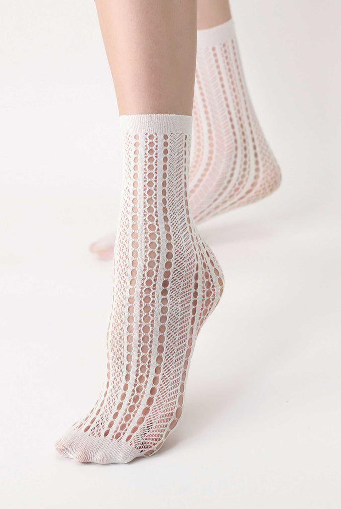 close up of lady's feet wearing white, patterned mesh socks.