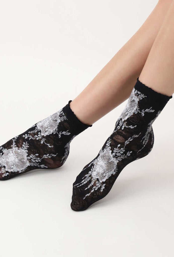 Front view of lady's feet in black and white floral socks.