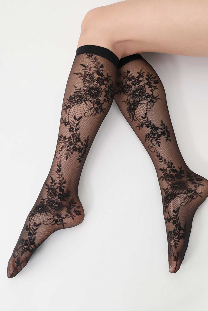 Black floral lace knee high socks modelled on a lady's legs.