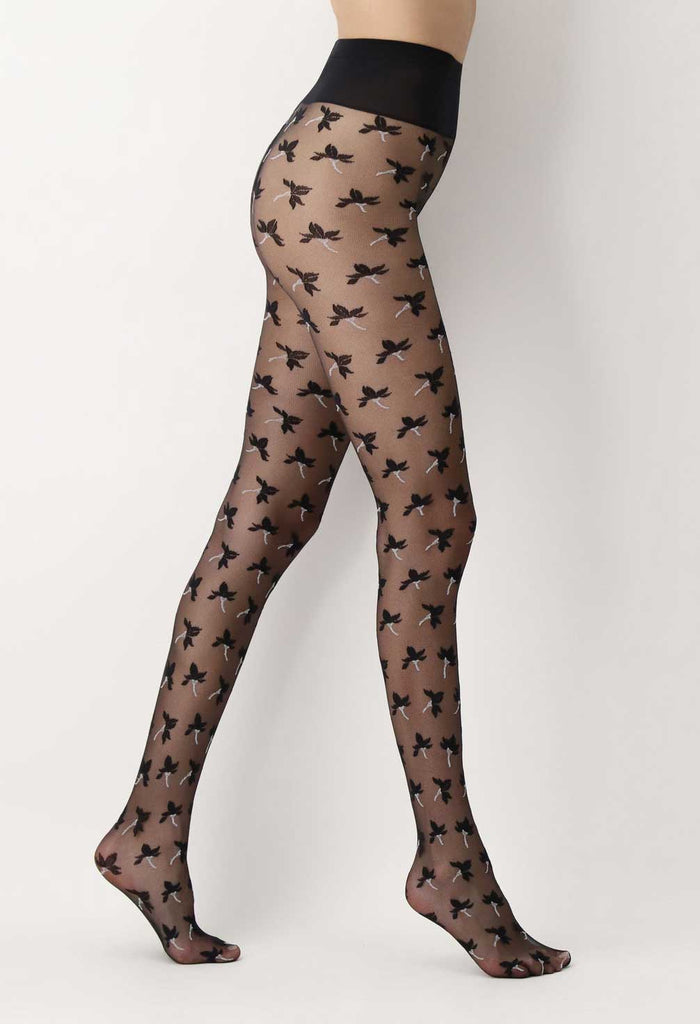 Side view of lady's legs walking stance, wearing black sheer tights, patterned with flowers.  Edit alt text