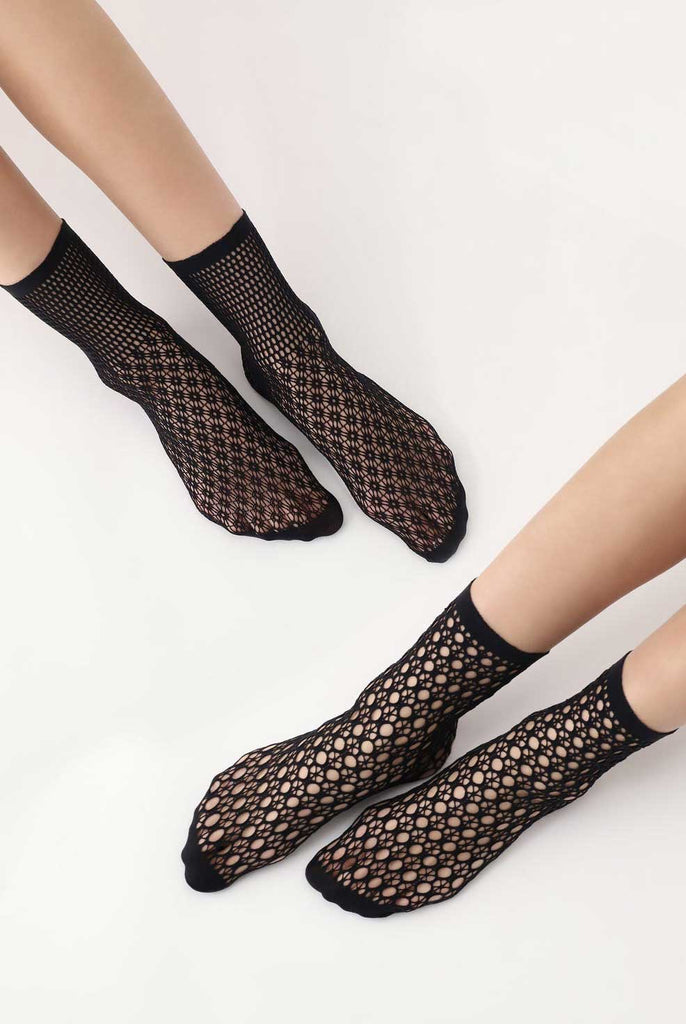 Two pairs of ladies feet wearing, black, pattern, mesh socks.