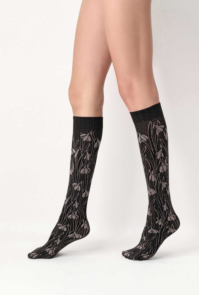 Side view of lady's lower legs, wearing black and beige floral knee highs