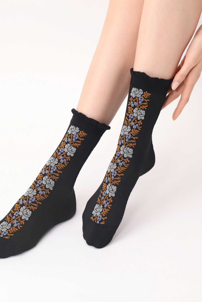 Front view of lady's feet, wearing black and coloured floral design socks.