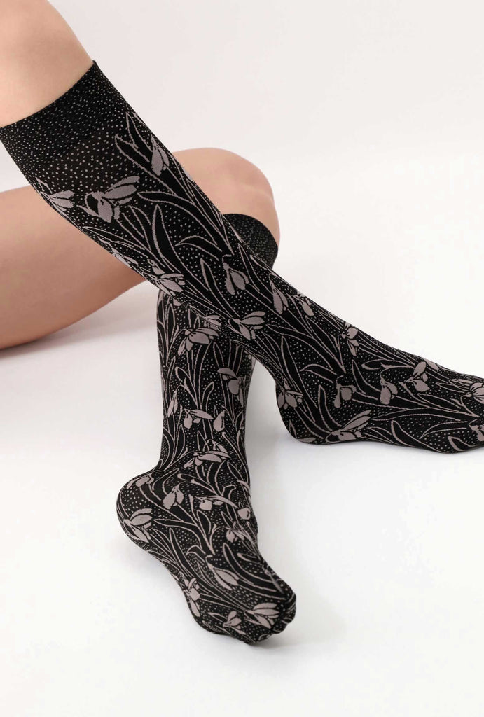 Outstretched feet wearing black and beige floral knee highs.