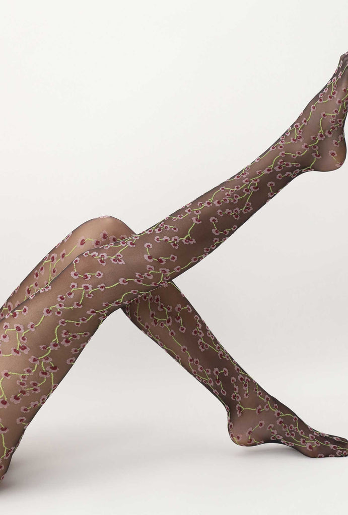 Side view of lady's outstretched leg, wearing black, sheer floral tights.