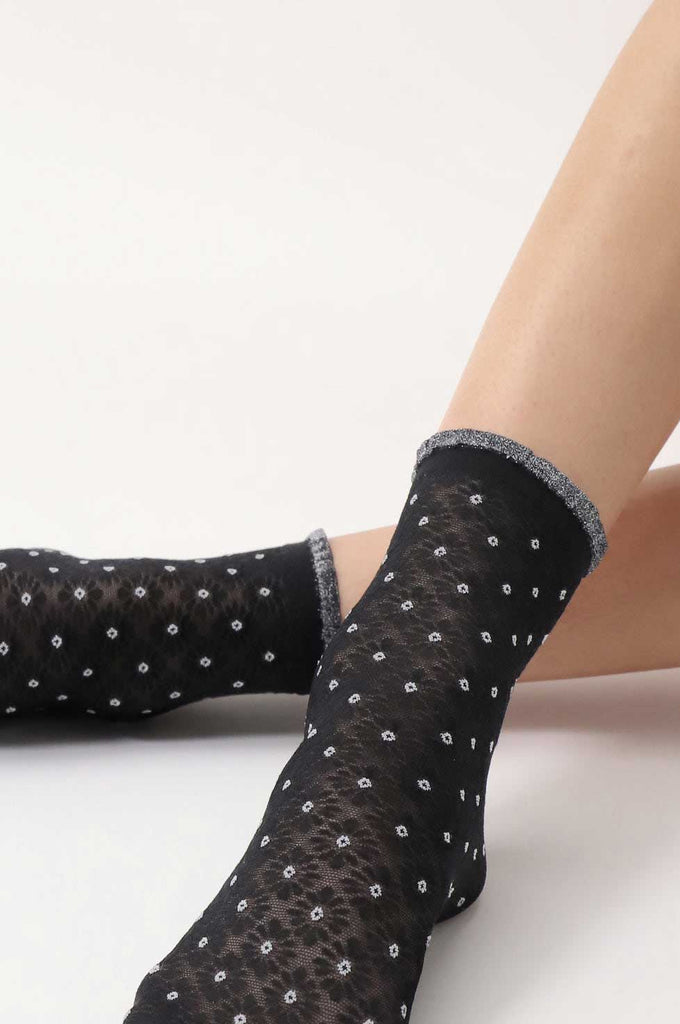 Close up of lady's feet wearing black, floral, motif socks
