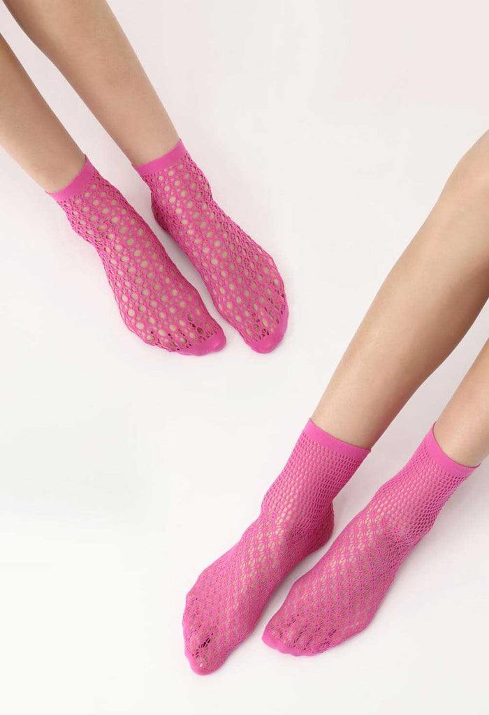Two pairs of women's feet wearing hot pink, patterned mesh socks.