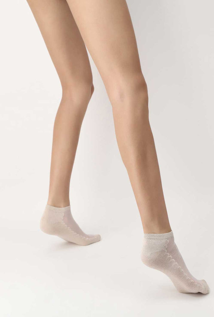 Lady's legs and feet wearing beige trainer socks.