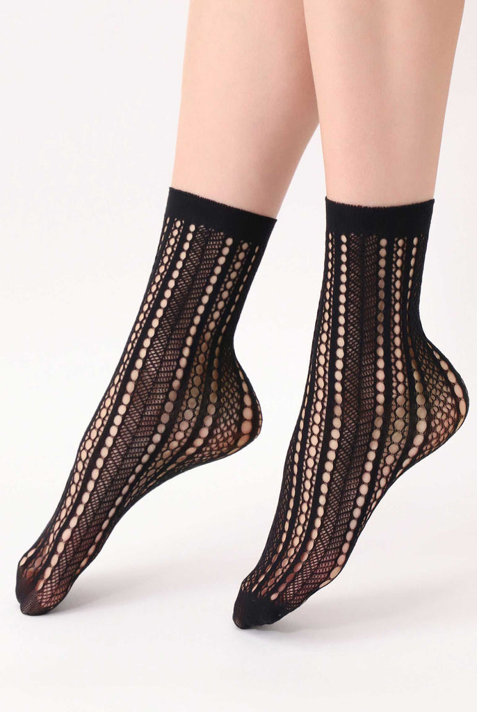 Side view of lady's feet wearing black mesh patterned socks.