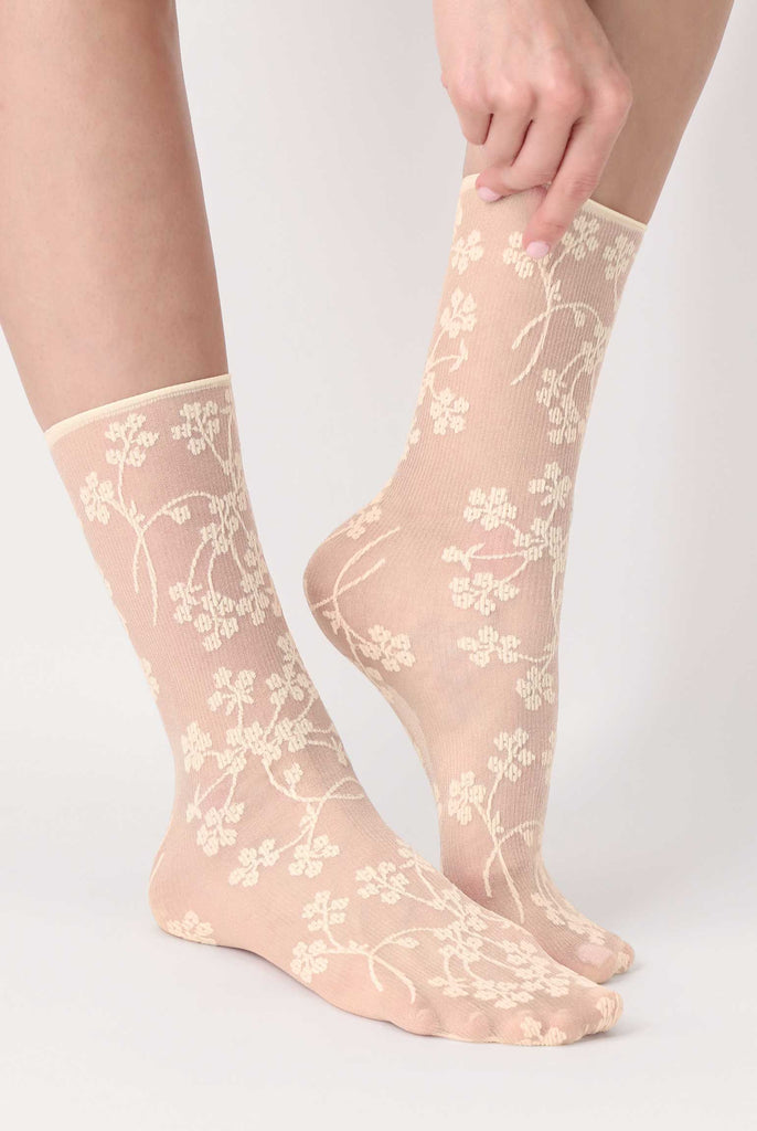 Close up of ladies feet, in cream, sheer, floral patterned, ankle socks.