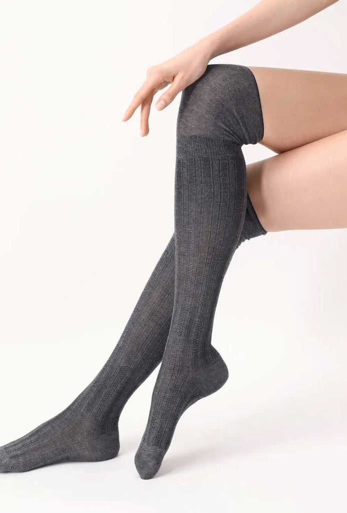 Ladies lower legs, crossed at the knees, in grey patterned long socks.