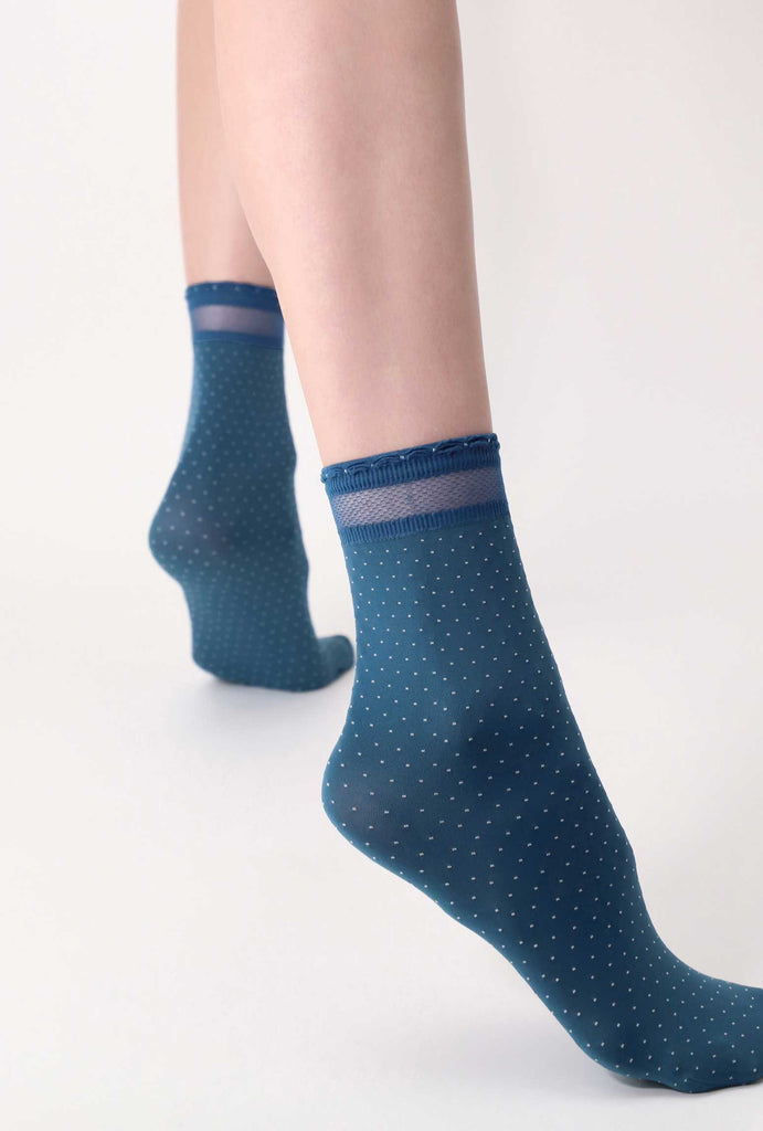 Lady's feet standing apart in cobalt blue and white dot socks.
