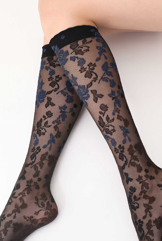 Close up of lady's lower legs extended in side V formation, in brown and blue floral knee highs.