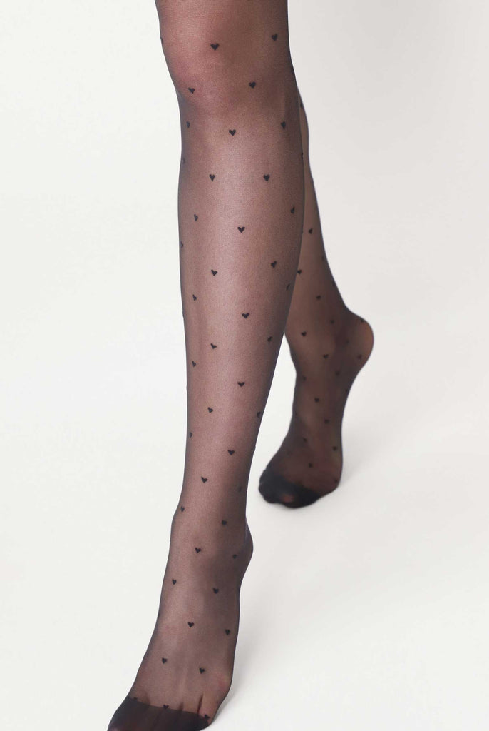 Lady's lower legs in walking stance wearing black heart patterned tights.