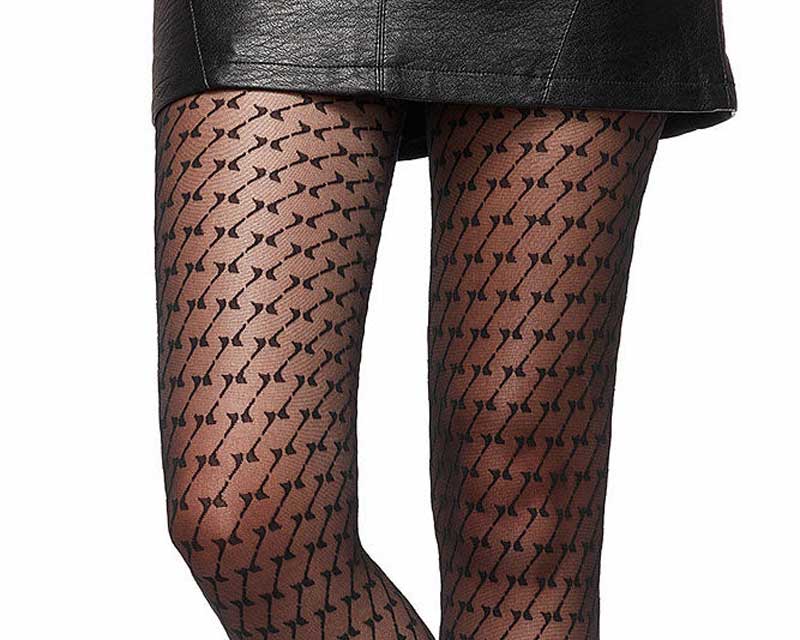 Woman's legs in bold geometric patterned sheer tights and black leather skirt, close-up from thighs to calves against white background.