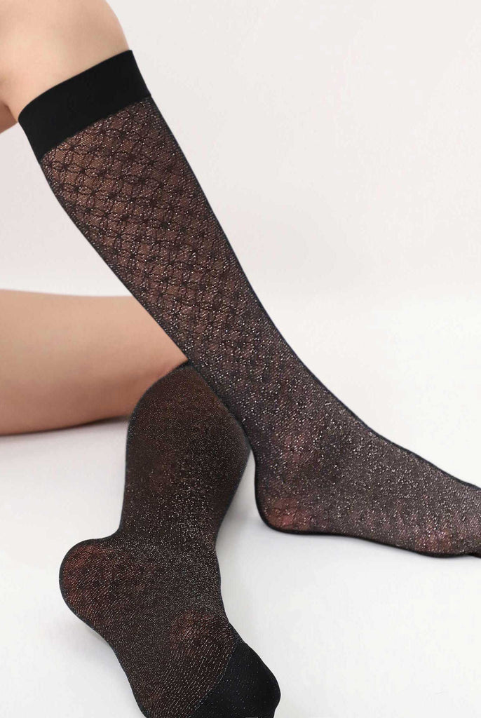 Side view of lady's legs wearing black sparkly lace knee high socks.
