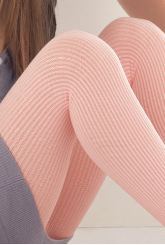 Close up of girl's legs sitting up wearing pale pink ribbed tights.