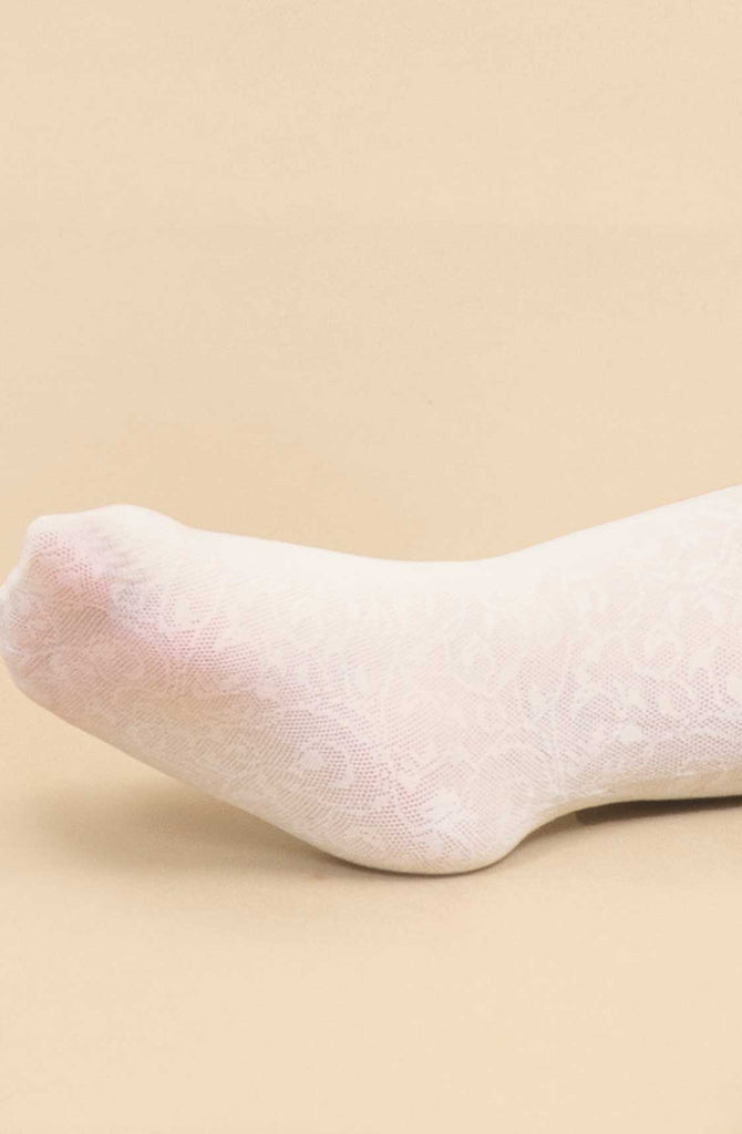 Close up of baby's foot in white lace floral tights.