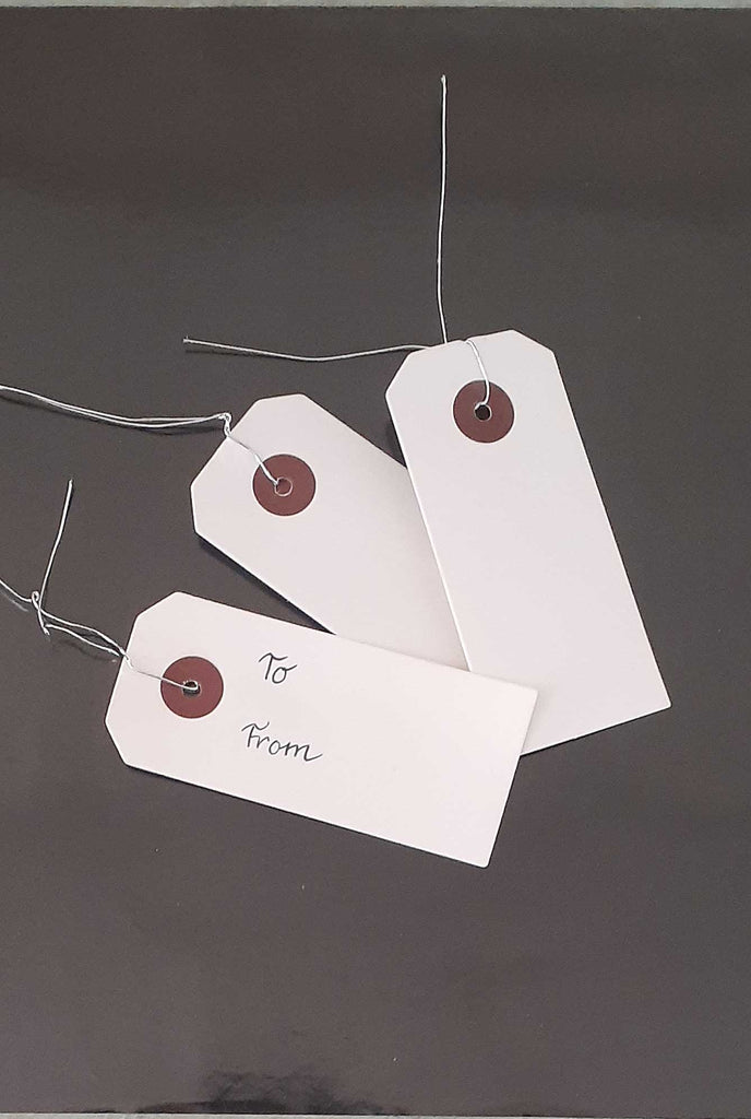 Three white gift tags, with silver ties attached.
