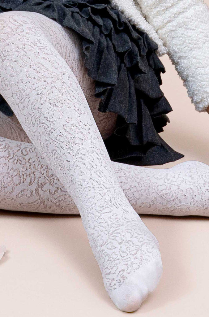 Close up of girls' lower leg and foot, wearing ivory floral lace tights.