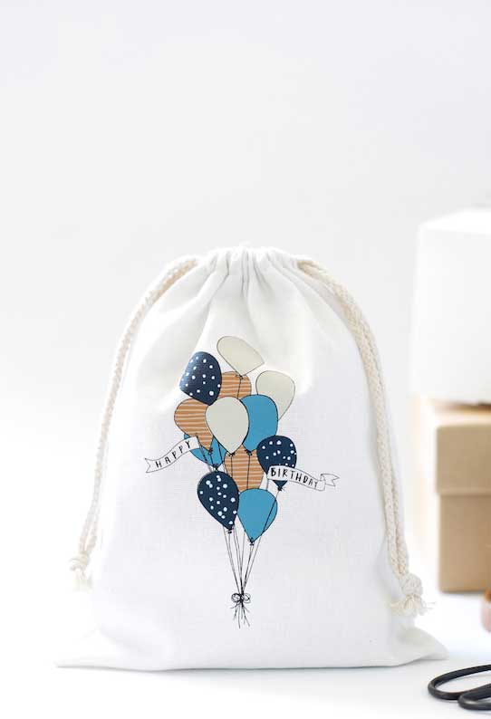 White bag with balloons illustration and the message Happy Birthday on the front.