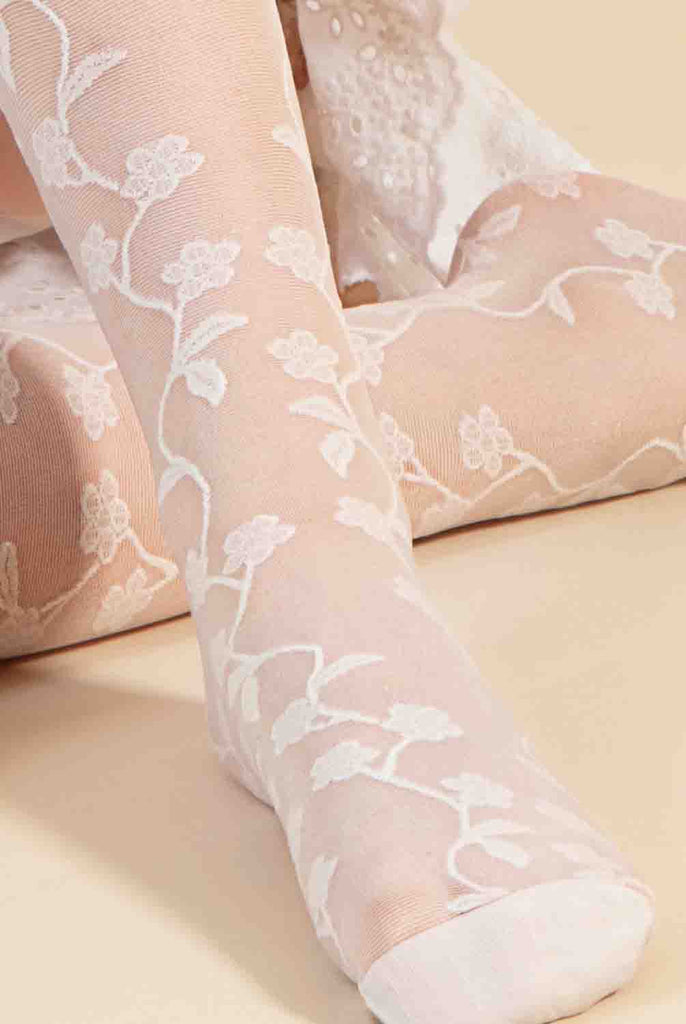 Close up of girl's foot with white floral sheer tights on.