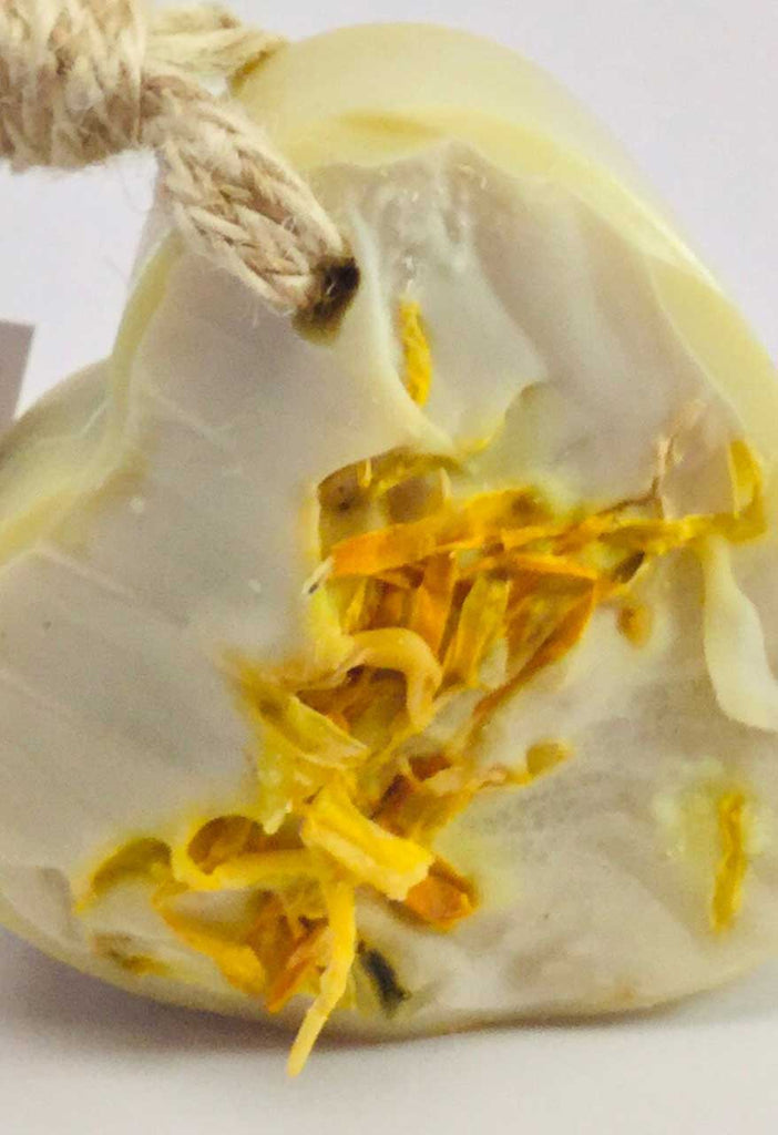 Close up of soap bar on a rope embedded with yellow calendula petals.